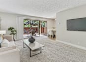 Thumbnail 7 of 90 - a living room with a tv and a sliding glass door at Summerwood Apartments, Santa Clara, 95050