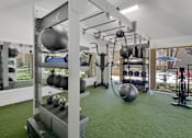 Thumbnail 78 of 90 - a gym with weights and other equipment on a green floor at Summerwood Apartments, Santa Clara