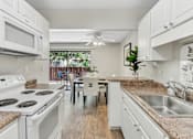 Thumbnail 29 of 90 - a kitchen with white appliances and granite counter tops at Summerwood Apartments, California