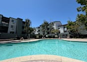 Thumbnail 20 of 21 - A swimming pool in front of apartment buildings.