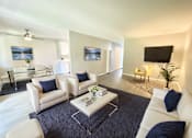 Thumbnail 4 of 18 - A living room with white furniture and a black flat screen TV.