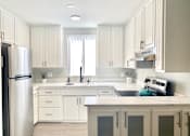 Thumbnail 13 of 31 - a white kitchen with white cabinets and a stainless steel refrigerator at The Flats on Addison, California