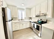 Thumbnail 1 of 31 - a white kitchen with stainless steel appliances and white cabinets at The Flats on Addison, Sherman Oaks, CA 91423