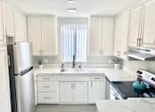 Thumbnail 14 of 31 - a white kitchen with stainless steel appliances and white cabinets at The Flats on Addison, California, 91423