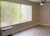 Thumbnail 12 of 39 - an empty living room with a large window and a ceiling fanat The Arches Apartments, LLC, El Cajon