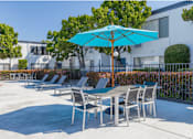 Thumbnail 6 of 39 - a patio with tables and chairs and an umbrellaat The Arches Apartments, LLC, El Cajon, 92021