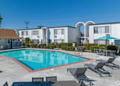 Thumbnail 8 of 39 - a swimming pool with chairs around it in front of a buildingat The Arches Apartments, LLC, El Cajon