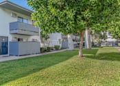 Thumbnail 8 of 18 - an apartment building with a lawn and trees in front of it at BLVD Apartments LLC, Tarzana, CA