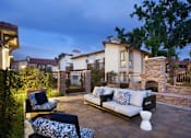 Thumbnail 21 of 44 - a patio with furniture and a stone fireplace at The Bryant, Yorba Linda, 92887