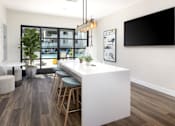 Thumbnail 13 of 27 - a kitchen with a long white counter top and a bar with stools at La Jolla Blue, San Diego, 92122
