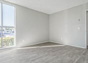 Thumbnail 37 of 39 - an empty living room with a large window and wooden floors at The Arches Apartments, California, 92021
