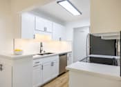 Thumbnail 17 of 83 - A kitchen with white cabinets and a black fridge at Summerwood Apartment , Santa Clara