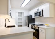 Thumbnail 20 of 83 - A kitchen with white cabinets and black appliances at Summerwood Apartment , California, 95050