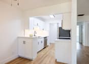 Thumbnail 18 of 83 - A kitchen with white cabinets and a wooden floor at Summerwood Apartment , California