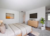 Thumbnail 7 of 83 - A bedroom with a large bed, a dresser, and a plant at Summerwood Apartment, Santa Clara, CA, 95050