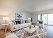 Thumbnail 2 of 83 - A living room with a white couch, a coffee table, and a painting on the wall at Summerwood Apartment , Santa Clara, 95050