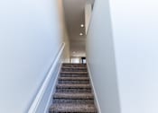 Thumbnail 43 of 45 - a view down the stairs of a hallway with carpeted stairs and white walls at The Vines at Riverpark, LLC, California, 93036