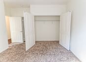 Thumbnail 39 of 45 - an empty bedroom with two doors leading to a walkin closet and a carpeted floor at The Vines at Riverpark, LLC, California, 93036