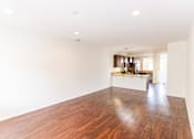 Thumbnail 42 of 45 - an empty living room and kitchen with wood floors and white walls at The Vines at Riverpark, LLC, California, 93036
