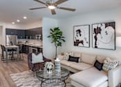 Thumbnail 62 of 78 - A living room with a white couch, a coffee table, and a ceiling fan.