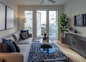 Thumbnail 61 of 78 - A living room with a white couch and a blue rug.