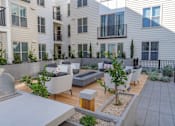 Thumbnail 56 of 78 - A patio area with a table and chairs is surrounded by apartment buildings.