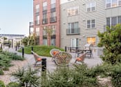 Thumbnail 58 of 78 - A modern apartment complex with a courtyard and seating area.
