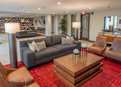Thumbnail 50 of 78 - A living room with a grey couch, a brown chair, and a wooden coffee table.