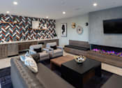 Thumbnail 51 of 78 - A modern living room with a grey couch and a fireplace.