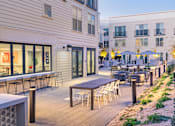 Thumbnail 48 of 78 - A patio with tables and chairs is surrounded by buildings.