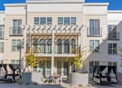 Thumbnail 45 of 78 - A modern two-story apartment building with a balcony and outdoor seating area.