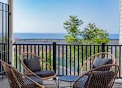 Thumbnail 17 of 78 - Two chairs and a table on a balcony overlooking the ocean.
