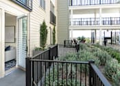 Thumbnail 18 of 78 - A black railing leads to a patio with a couch and a tree.