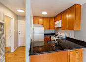 Thumbnail 5 of 9 - A kitchen with wooden cabinets and a black countertop.