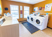Thumbnail 11 of 14 - A laundromat with a washer and dryer and a flat screen TV.