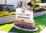 Thumbnail 1 of 9 - A sign for Courtyard Apartments is in front of a building.