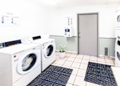Thumbnail 8 of 9 - A laundry room with washing machines and a door.