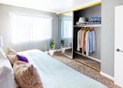 Thumbnail 4 of 9 - A bedroom with a bed, pillows, a plant, and a closet.