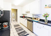 Thumbnail 3 of 9 - A kitchen with black countertops and white cabinets.