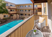 Thumbnail 6 of 9 - A balcony with a table and chairs overlooking a pool.