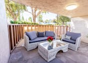 Thumbnail 6 of 13 - A patio with a grey couch, a grey sofa, and a grey coffee table.