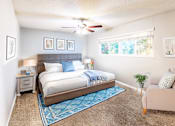 Thumbnail 2 of 8 - A bedroom with a bed, a chair, and a ceiling fan.