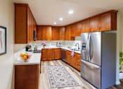 Thumbnail 4 of 11 - A kitchen with wooden cabinets and a stainless steel refrigerator.