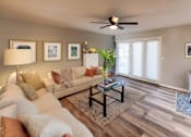 Thumbnail 3 of 11 - A living room with a white couch, a coffee table, and a ceiling fan.