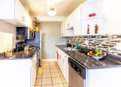 Thumbnail 3 of 11 - A kitchen with black granite countertops and white cabinets.