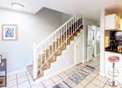 Thumbnail 4 of 11 - A staircase with a white railing and beige carpeted steps leads to a kitchen area.