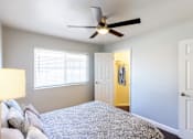 Thumbnail 5 of 11 - A bedroom with a bed, a ceiling fan, and a yellow door.