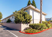 Thumbnail 1 of 11 - A white building with a red border around the bushes.