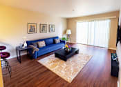 Thumbnail 5 of 9 - A living room with a blue couch and a coffee table.