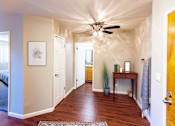 Thumbnail 3 of 9 - A hallway with a ceiling fan and a rug on the floor.